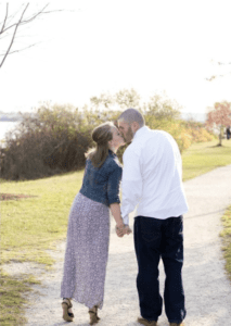 Romantic couple holding hands and kissing on the Eastern Promenade in Portland, ME, an example of fun date ideas that support connection in couples therapy.